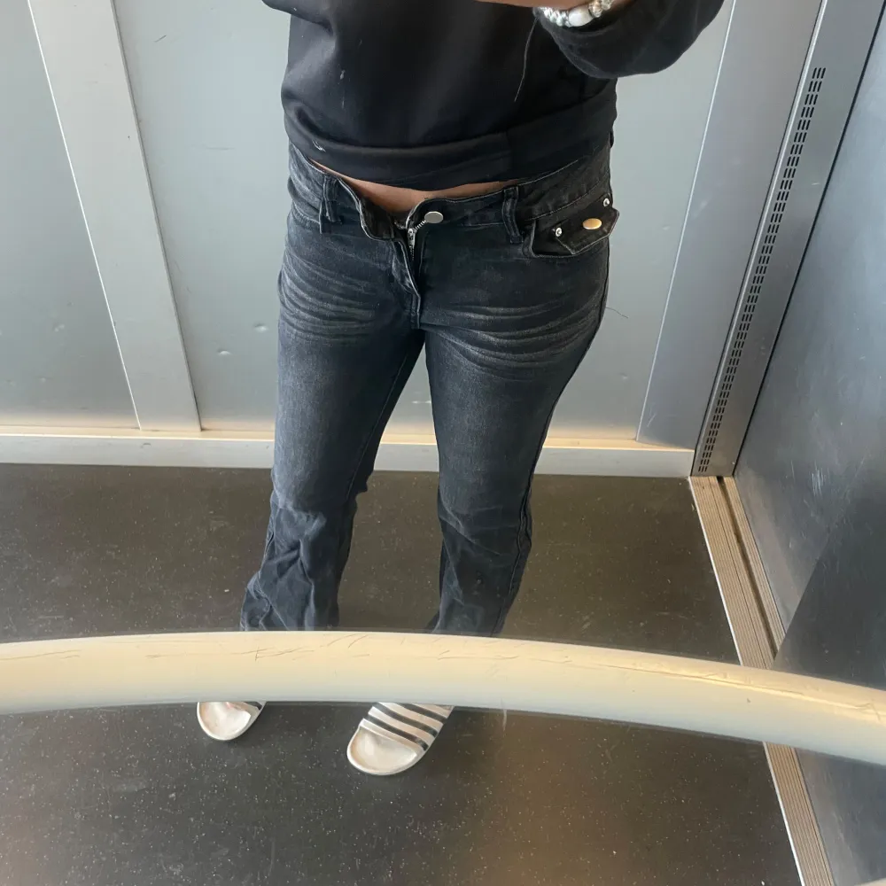 Säljer ett par svarta jeans med bootcut o low waist. De har en snygg och klassisk look med knappar och dragkedja framtill. Perfekta för både vardag och fest!. Jeans & Byxor.