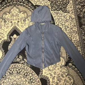 Blå  hoodie från NA-KD - Säljer en snygg blå hoodie från NA-KD med dragkedja framtill. Jackan har en croppad design och är tillverkad i ett mjukt material. Perfekt för en avslappnad stil.