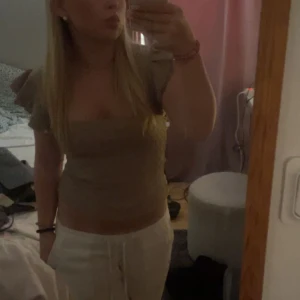Beige topp med volangärmar - Säljer en stilren beige topp med volangärmar. Toppen har en tight passform och är perfekt för en trendig look. 