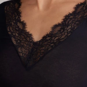 Intimissimi - Elegant svart långärmad topp med v-ringad spetsdetalj vid halsen och spets vid ärmsluten. Perfekt för en stilren look.