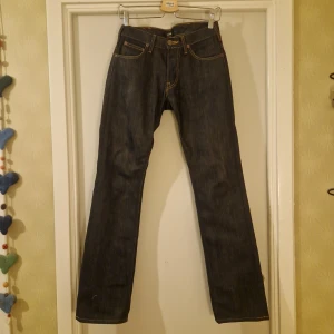 Mörkblå jeans från Lee - Snygga mörkblå jeans från Lee med klassisk design. De har en rak passform och är tillverkade i slitstarkt denim. Byxorna har fem fickor och en knappgylf med Lee-logotypen på knappen. Perfekta för en stilren look. Längd 32