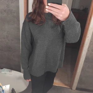 Grå stickad tröja - Säljer en mysig grå stickad tröja med långa ärmar. Perfekt för kyliga dagar och enkel att matcha med olika outfits. Tröjan har en klassisk design och är ett måste i garderoben.