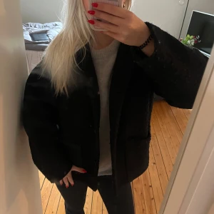 Svart kappa  - Säljer en stilren svart kappa med knappar framtill. Jackan har stora fickan framtill. Lite nopprig men inget som är ett problem. Xs men skulle snarare säga S