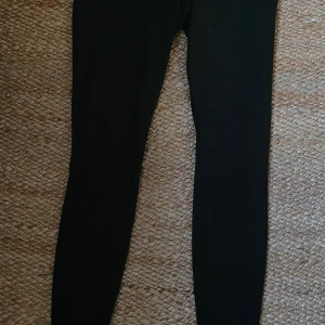 Svarta Dri-FIT leggings från Nike - Snygga svarta leggings från Nike med Dri-FIT-teknologi. Perfekta för träning och tillverkade av återvunna material. De har en tight passform som ger bra stöd under aktivitet.