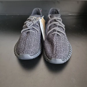  YEEZY BOOST 350 (Pirate black) - Snygga Adidas Yeezy Boost 350 sneakers i en stilren svart färg. Skorna har en stickad ovandel med snörning och en bekväm sula med Boost-teknologi. Perfekta för en trendig look..Har order bekräftelse från Adidas för att bevisa att de är äkta.