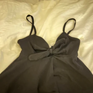 Svart linnetopp från Gina Tricot - Snygg svart linnetopp från Gina Tricot med smala axelband och en knytdetalj framtill. 