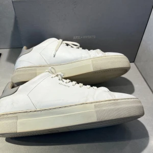Vita sneakers från Axel Arigato - Snygga vita sneakers från Axel Arigato med stilren design. Skorna har en klassisk snörning och en robust sula. Perfekta för en härlig look. Dom har gått sönder därbak på ena skon som man ser på sista bilden och så är dom lite missfärgade därav priset, på 499kr men man får 10% rabatt om man blir en följare så då får man dom för 449kr. Jag skickar gärna fler bilder. Ställ gärna frågor!