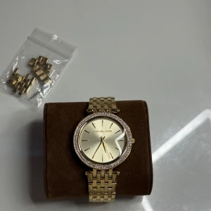 Michael kors klocka  - Michael kors klocka i guld. Man får med extra länkar och verktyg för att minska och förstora den. Behövs byta batteri på den. Ny pris ca 1900kr mitt pris 1099kr