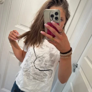 Vit t-shirt från Zara - Säljer en vit t-shirt från Zara med ett abstrakt tryck på framsidan. T-shirten har korta ärmar och en normal passform. Perfekt för en avslappnad stil.