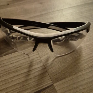 Innebandy glasögon från Energy - Säljer ett par sportiga glasögon från Energy med svart och vit båge. Perfekta för träning med sin lätta och bekväma design. Kommer med ett praktiskt fodral för enkel förvaring.