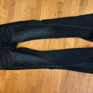 Mörkblå jeans från True Religion - Snygga mörkblå jeans från True Religion med låg midja och bootcut-stil. De har dekorativa sömmar och knappar på bakfickorna. Passar perfekt med alla outfits.