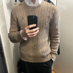 Brun kabelstickad tröja från Ralph Lauren - Helt ny, använd enstaka gång. Inget slitage eller tecken på användning. Nypris är ca 2000.  Säljes pga garderobsrensing. Skriv vid minsta fundering!