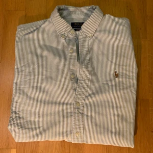 Randig Skjorta Ifrån Ralph Lauren  - Säljer denna riktigt snygg skjorta ifrån Ralph lauren perfekt nu inför sommaren. Skjortan är i bra skick och köptes för nypris 1599kr. Skriv direkt vid frågor så löser vi en bra deal. 