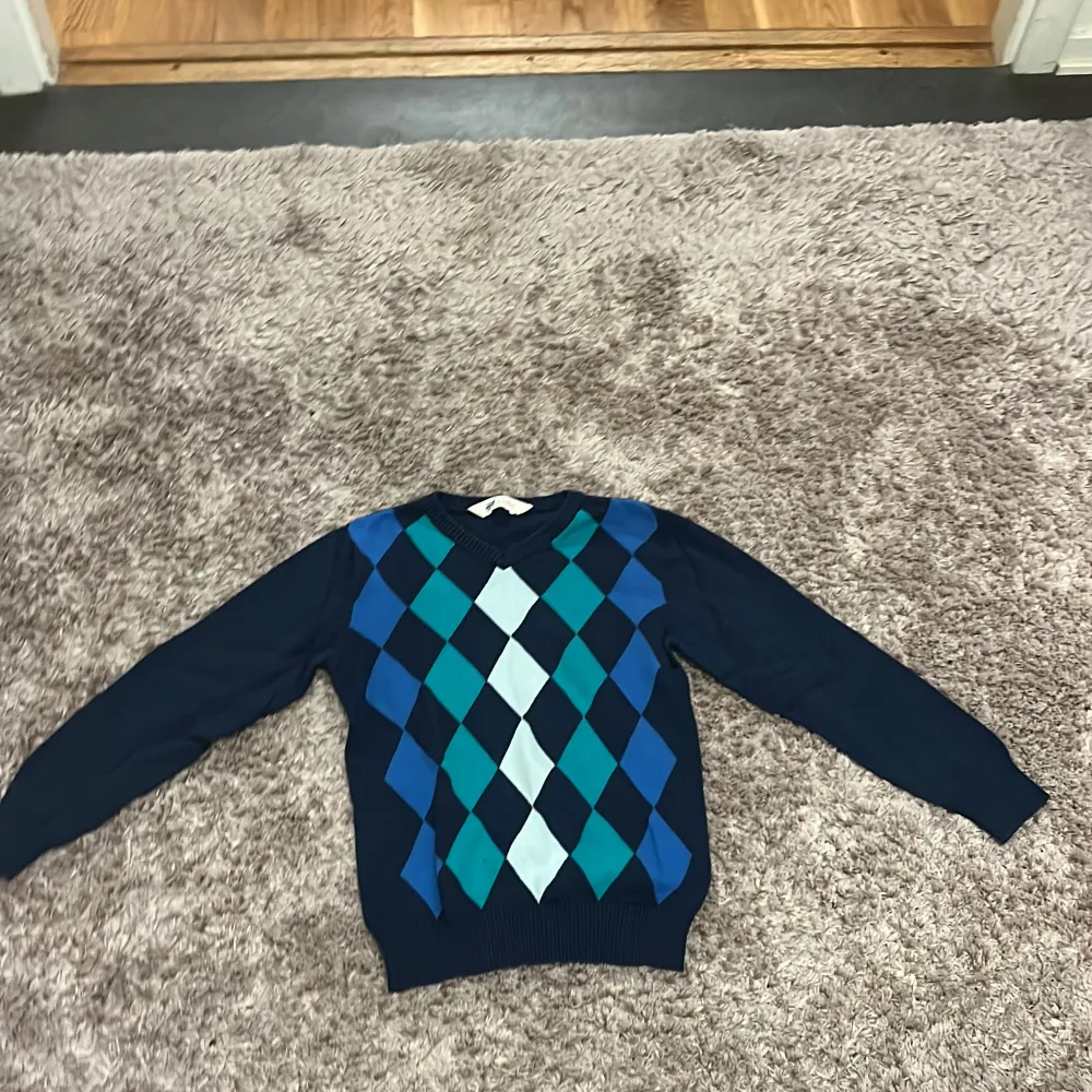 Säljer en snygg tröja från H&M med ett klassiskt argylemönster i blått, turkos och vitt. Tröjan har långa ärmar och en bekväm passform, perfekt för kyligare dagar.. Neuletakit & Villapaidat.