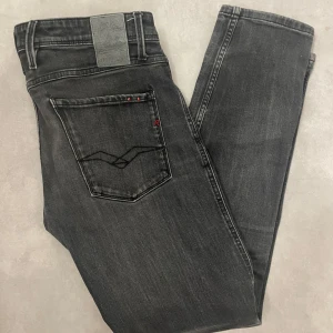 Grå Replay Anbass jeans - Snygga grå Replay Anbass jeans med en klassisk femficksdesign och diskreta detaljer. De har en bekväm passform och är perfekta för en stilren look. Märkeslogga på bakfickan och knappstängning fram. Hör av dig om du har några frågor!