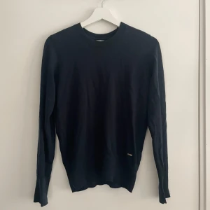 Svart tröja från Holly & Whyte by Lindex - Snygg mörkblå tröja från Holly & Whyte by Lindex i storlek S. Tröjan har långa ärmar och dekorativa knappar vid ärmsluten. Perfekt för en stilren look.