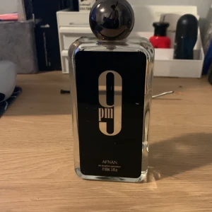 9pm Eau de Parfum från Afnan - Säljer en flaska 9pm Eau de Parfum från Afnan. Flaskan är rektangulär med en stilren svart etikett och en stor svart kork. doft som passar perfekt för kvällsbruk. Perfekt för den som vill ha en elegant och modern doft.