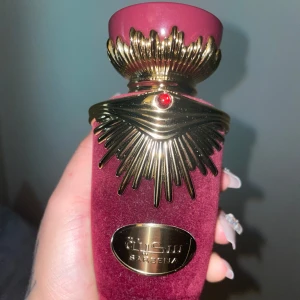 Lyxig parfymflaska i röd sammet - ( Mer än halv )Elegant parfymflaska klädd i röd sammet med detaljer i guld och en röd juvel. Flaskan har en unik design med en dekorativ guldkrona på toppen. Perfekt för den som vill ha något exklusivt och iögonfallande på sminkbordet.