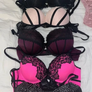 Färgglada spetsbehåar i olika stilar/ S - Säljer ett set med fyra behåar i olika färger och mönster. En svart med glittriga prickar, en rosa med svart spets, en vinröd med spetsdetaljer och en ljusrosa med svarta band. Perfekt för att mixa och matcha!