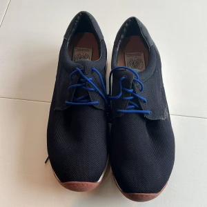 Svarta sneakers från Vagabond - Snygga svarta sneakers från Vagabond med blå snörning och en robust sula. Perfekta för en stilren look med en touch av färg. Märket Sneaky Steve syns på insidan.