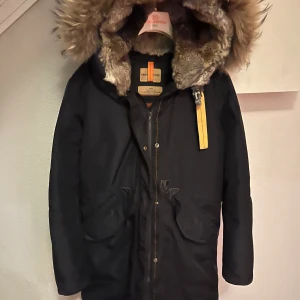 Mörk blå  parkajacka från Parajumpers - Säljer en mörk blå parkajacka från Parajumpers i mycket bra skick. Jackan har en mysig pälsfodrad huva och dragkedja framtill. Perfekt för kalla vinterdagar. Den är både stilren och funktionell, med flera praktiska fickor.