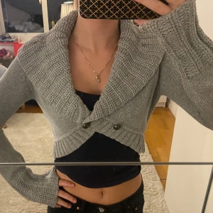 Grå stickad bolero 🥰 - Säljer en superfin grå stickad kofta med stora knappar framtill. Den är croppad och har en mysig, oversized krage. Perfekt för höst och vinter när du vill vara både stilren och varm. Passar perfekt över en enkel topp för en avslappnad look. Från Zeol 