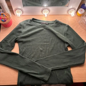 Grön ribbad tröja från FB Sister💚 - Säljer en snygg grön ribbad tröja från FB Sister i storlek S. Perfekt för höst och vår med sin långärmade design. Tröjan är i bra skick och passar både till vardags och lite finare tillfällen. Superbekväm och lätt att matcha med andra plagg! 🍃