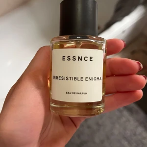Irresistible Enigma Eau de Parfum från Essnce - Säljer en flaska Irresistible Enigma Eau de Parfum från Essnce. Doften är en mystisk blandning av päron, apelsin och blommiga toner. Flaskan är stilren och elegant med en svart kork och en enkel vit etikett. Perfekt för både dag och kväll! 🌟 Mycket kvar i som syns på bilderna🥰