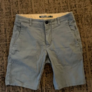 Grå shorts från WinWin - Säljer ett par stilrena grå shorts från WinWin i storlek XS. De har en klassisk design med knapp och dragkedja framtill samt fickor både fram och bak. Perfekta för en avslappnad sommarstil!