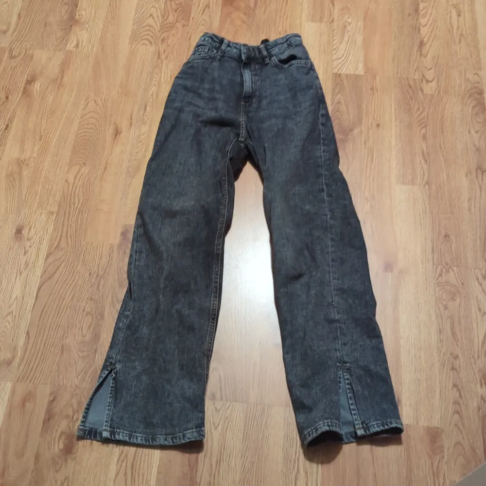 Säljer ett par grå jeans i bra skick. De har en loose passform och är högmidjade. Byxorna har en cool slitsdetalj vid bensluten som ger dem en unik stil. Perfekta för höst och vår!. Jeans & Byxor.