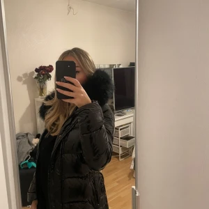 Svart glansig pufferjacka med pälshuva - Säljer en superfin svart pufferjacka med glansigt material och stor pälshuva från femenina of sweden. Perfekt för kalla vinterdagar! Jackan har en dragkedja framtill och är långärmad. Den är oanvänd. 🖤den är i strl XS men passar även S! 