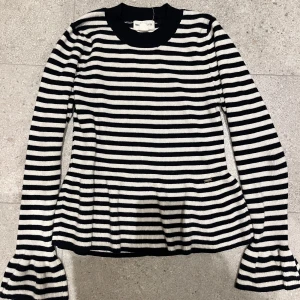 Randig peplum topp - Säljer en superfin randig tröja från Holly & Whyte i blå och vitt. Den har långa ärmar med volangdetaljer och är utsvängd på botten 