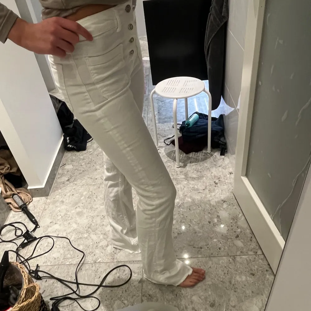 Säljer ett par snygga vita högmidjade byxor i mycket bra skick. De har en tight passform och fem knappar framtill som ger en cool detalj. . Jeans & Byxor.