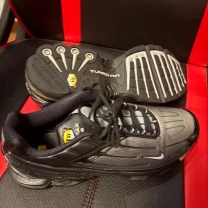 Svarta Nike Tuned Air sneakers - Säljer ett par svarta Nike Tuned Air sneakers i bra skick. De har en cool design med svarta och grå detaljer och är perfekta för både träning och vardagsbruk. Skorna har snörning och en bekväm passform. Skorna kommer även i Nike sko boxen! Priset kan diskuteras 