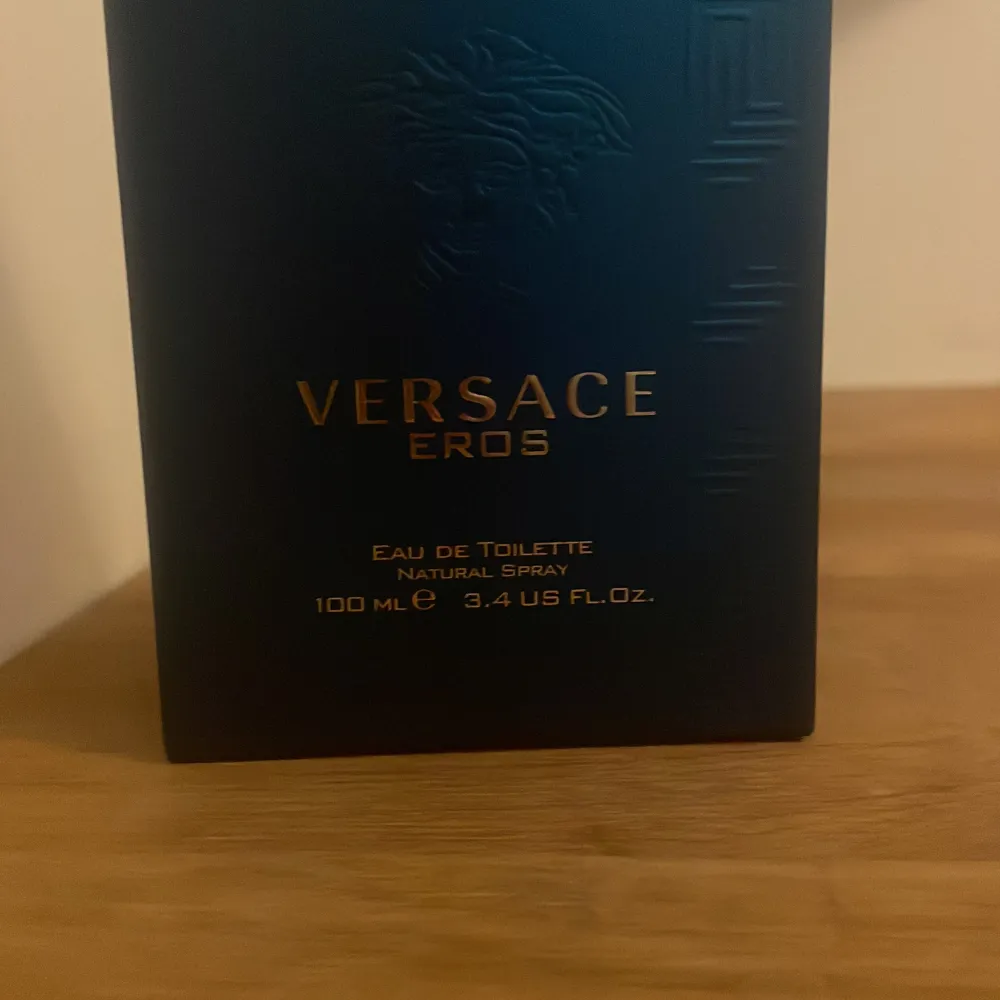 Säljer en flaska Versace Eros Eau de Toilette, 10ml. Flaskan är i en snygg blå färg med gulddetaljer och har en elegant design. Perfekt för den som vill ha en fräsch och maskulin doft. Flaskan är nästan full och kommer med en praktisk resestorlek.     OBS ÄR BARA 10 ml inte 100. Parfym.