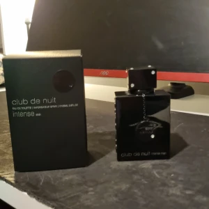 Club de Nuit Intense Man Eau de Toilette - Säljer en elegant och intensiv herrparfym från Armaf, Club de Nuit Intense Man. Flaskan är svart och stilren med en fyrkantig form och en liten kedja som detalj. Perfekt för kvällar ute eller speciella tillfällen. Kommer i originalförpackning. Har ungefär använt 5 ml