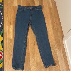Blå slim fit jeans från H&M - Säljer ett par blå slim fit jeans från H&M i storlek 164. De har justerbar midja för perfekt passform och är i bra skick. Perfekta för vardagsbruk med en klassisk stil och bekväm passform.
