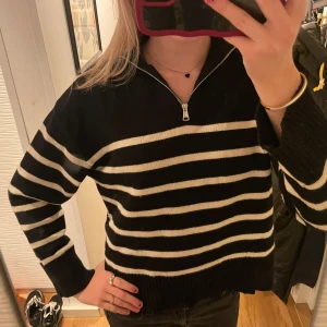 Svart och vit randig tröja med dragkedja - Säljer en snygg svart tröja med vita ränder och en dragkedja vid halsen. Perfekt för höst och vinter! Den har långa ärmar och en bekväm passform. Superfin att matcha med jeans eller kjol. Hör av dig vid intresse! 🖤🤍