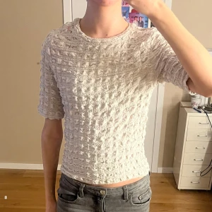 Beige topp från Lindex - Säljer en superfin beige topp från Lindex i storlek XS. Den har en unik textur och korta ärmar. Toppen är i mycket bra skick!! Endast använd 3 gånger!!