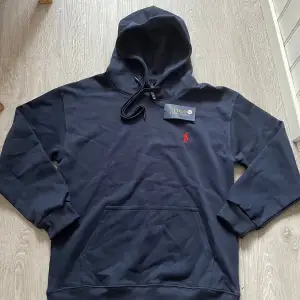 Säljer en snygg svart hoodie från Ralph Lauren i storlek M. Den har en klassisk design med en röd broderad logga på bröstet och en praktisk magficka. Perfekt för både höst och vinter, och den är superbekväm att ha på sig. Huvan har dragsko för justering. Passar perfekt till vardags