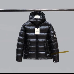 Svart dunjacka från Moncler - Säljer en snygg svart dunjacka från Moncler. Den är perfekt för vintern med sitt pufferdesign och har en praktisk huva. Jackan har dragkedja och knappar framtill samt två fickor med dragkedja. Den är i mycket bra skick och redo för kalla dagar.