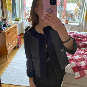 Tunnare jacka/kofta med guld detaljer  - Säljer en superfin tunnare jacka/kofta med detaljer vid krage och ärmslut. Kavajen har en normal passform och är perfekt för höst och vår. Den har knappar framtill och två fickor med knappdetaljer. Passar både till vardags och fest! Står ingen storlek men skulle säga att den passar XS/S.