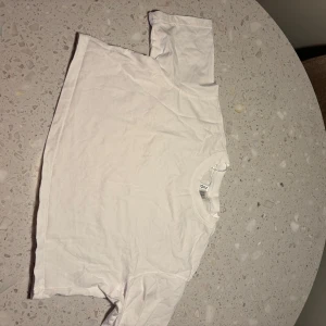 Vit croppad t-shirt från Divided h&m - Säljer en enkel och stilren vit t-shirt croppad från Divided i storlek XS. Perfekt basplagg för alla tillfällen. T-shirten är kortärmad och gjord i mjukt bomullsmaterial. Passar både till vardags och fest. 🕊️finns även i S