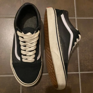 Fodrade Vans i skinn.  - Säljer ett par klassiska svarta sneakers med vit rand och snörning. De är i bra skick och har en snygg retrostil. Perfekta för vardagsbruk och passar till det mesta. Storleken är US Men 4.5 och Women 6.
