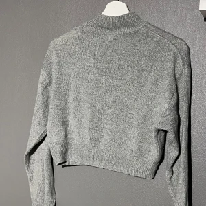 Grå stickad tröja från H&M Divided - Säljer en mysig grå stickad tröja från H&M Divided. Tröjan har en ribbad kant vid halsen och är i mycket bra skick. Endast använd ett fåtal gånger. Storlek XXS. Köparen står för frakten 