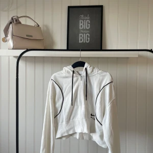 Vit croppad hoodie från Nike - Säljer en superfräsch vit croppad hoodie från Nike. Den har en dragkedja framtill och svarta detaljer som ger en snygg kontrast. Perfekt för en avslappnad stil eller träning. Hoodien är i mycket bra skick och redo för nya äventyr!