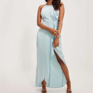 Ljusblå långklänning med slits - Balklänning från nelly i storlek 32, passar även 34. Helt oanvänd med prislappar kvar. Nypris 800kr. 