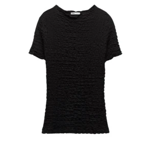 Svart texturerad topp från Zara - Snygg svart topp från Zara med en unik textur som ger en cool look. Den har korta ärmar och en normal passform, perfekt för både vardag och fest. En mångsidig topp som funkar året runt!