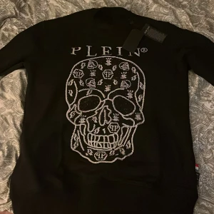 Svart tröja med dödskalle från Philipp Plein - Säljer en svart tröja från Philipp Plein med en stor, glittrig dödskalle på framsidan. Tröjan har långa ärmar och är i mycket bra skick. Perfekt för en cool och edgy look! 🖤 Passar M/L                           PRIS KAN DISKUTERAS!🩶🤍🩶🤍