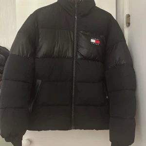 Svart pufferjacka från Tommy Jeans - Svart puffer jacket från Tommy Hilfiger i storlek S. Jackan är i mycket bra skick och passar bra framåt kallare årstider.   Jackan kan skickas med föredraget är att jackan köps på plats. Du får gärna komma och titta på jackan om du vill! Vid snabb och smidig affär kan priset diskuteras.   Hör gärna av er vid frågor eller för fler bilder. Finns i Örebro!  / Richard